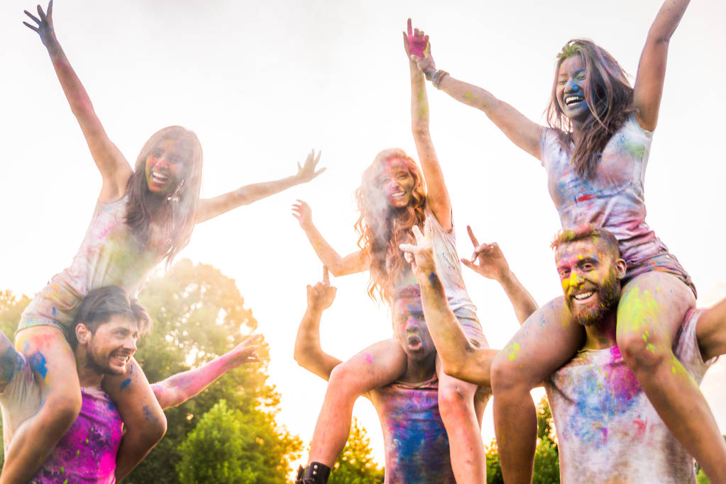 Группа счастливых друзей, играющих цветами цвета холи в парке - Молодые люди веселятся на фестивале холи, концепция веселья, веселья и молодого поколения
 - Фото, изображение