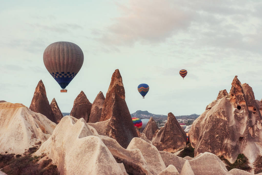 Heißluftballon fliegt über Felslandschaft in Kappadokien Türkei. Tal, Schlucht, Hügel, gelegen zwischen den vulkanischen Bergen im Goreme-Nationalpark. - Foto, Bild