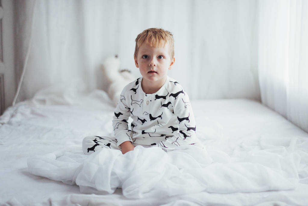 ベッドで遊ぶソフト暖かいパジャマの子 - 写真・画像