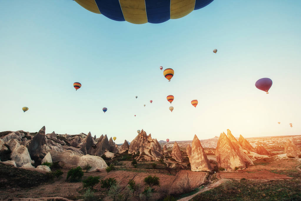 Colorful hot air balloons flying over Red valley at Cappadocia, Anatolia, Turkey. Volcanic mountains in Goreme national park. - Photo, Image