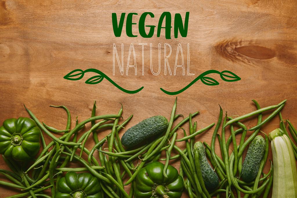 Green beans and organic vegetables on wooden table with "vegan natural" lettering - Photo, Image
