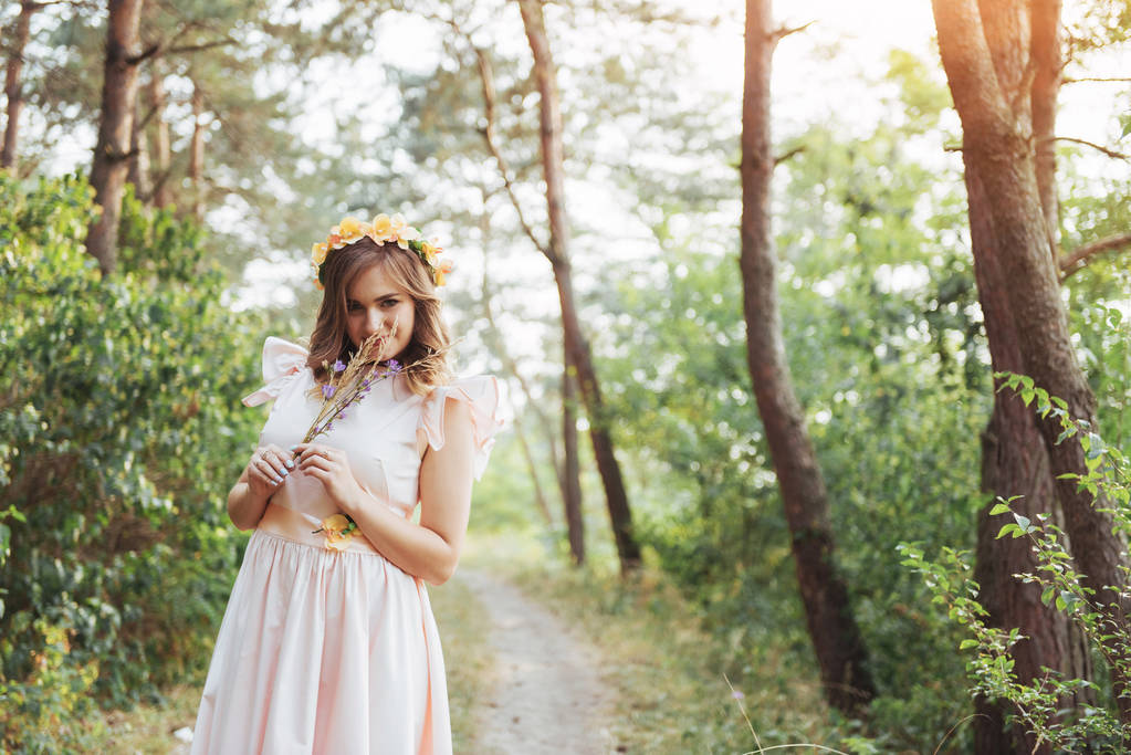 Happy young woman in a long dress in a beautiful pine forest in summer sunny day. - Photo, Image