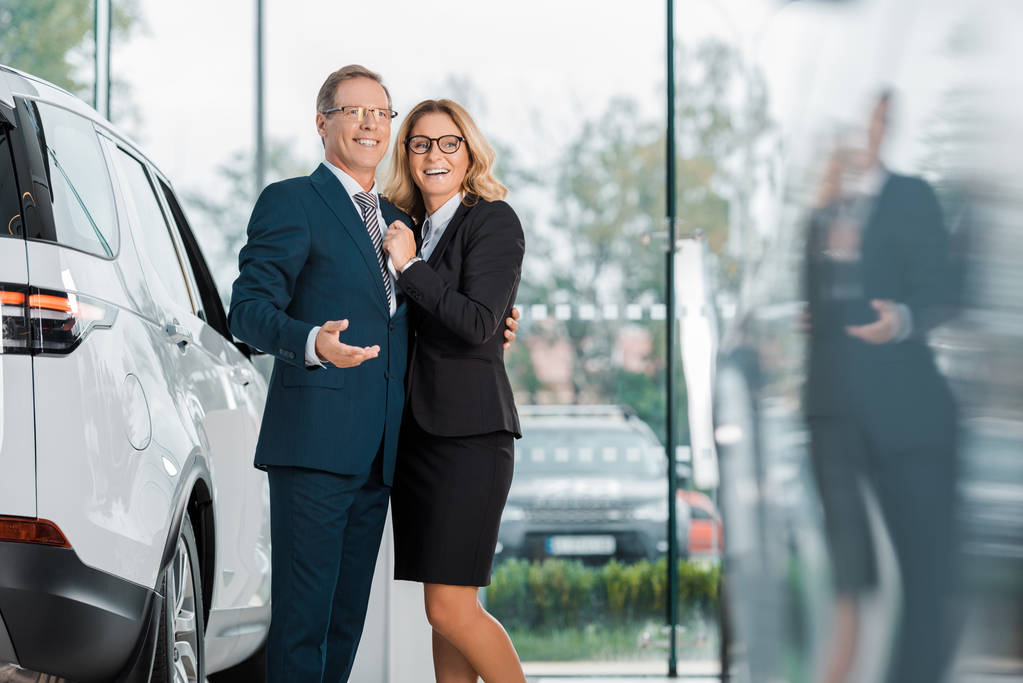 usmívající se obchodní pár hledá nový automobil v autorizovaném salonu - Fotografie, Obrázek