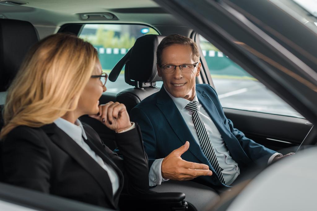 sonriente pareja de negocios sentado en un coche nuevo para la prueba de conducción
 - Foto, Imagen