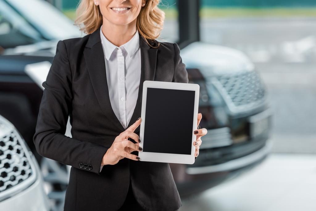 plan recadré de concessionnaire de voiture femme tenant tablette avec écran blanc au showroom
 - Photo, image