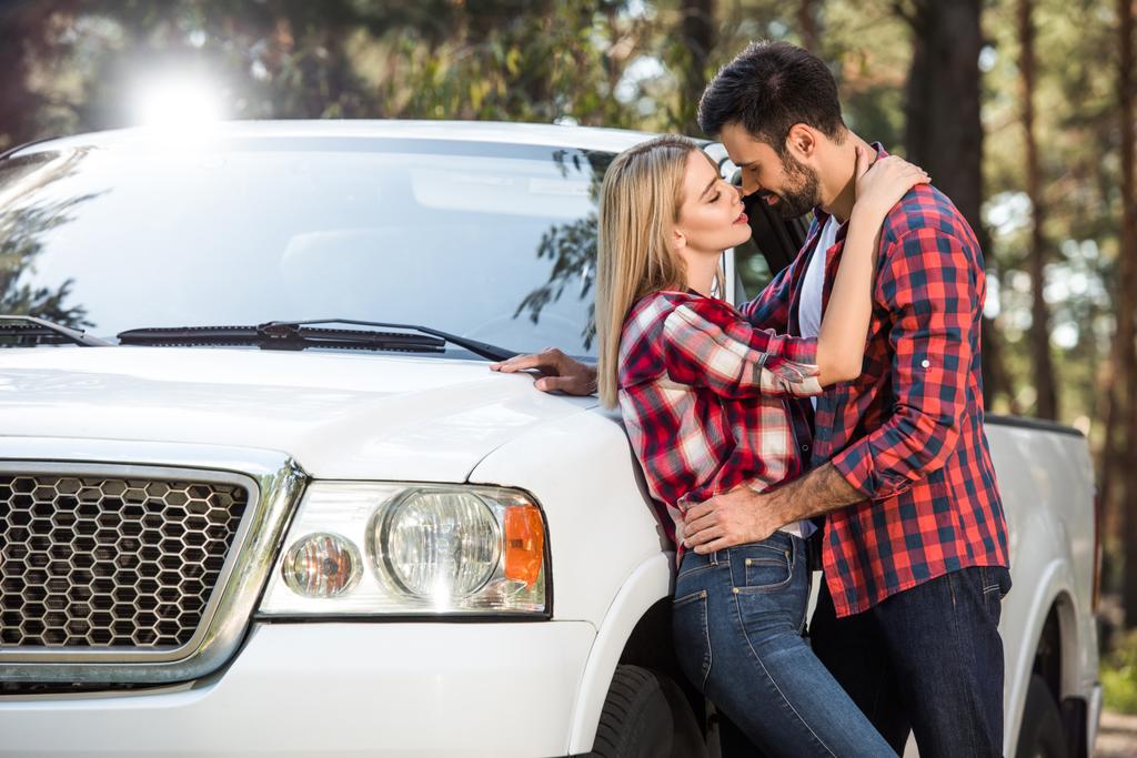 sonriente joven pareja mirando el uno al otro cerca recoger el coche al aire libre
  - Foto, imagen
