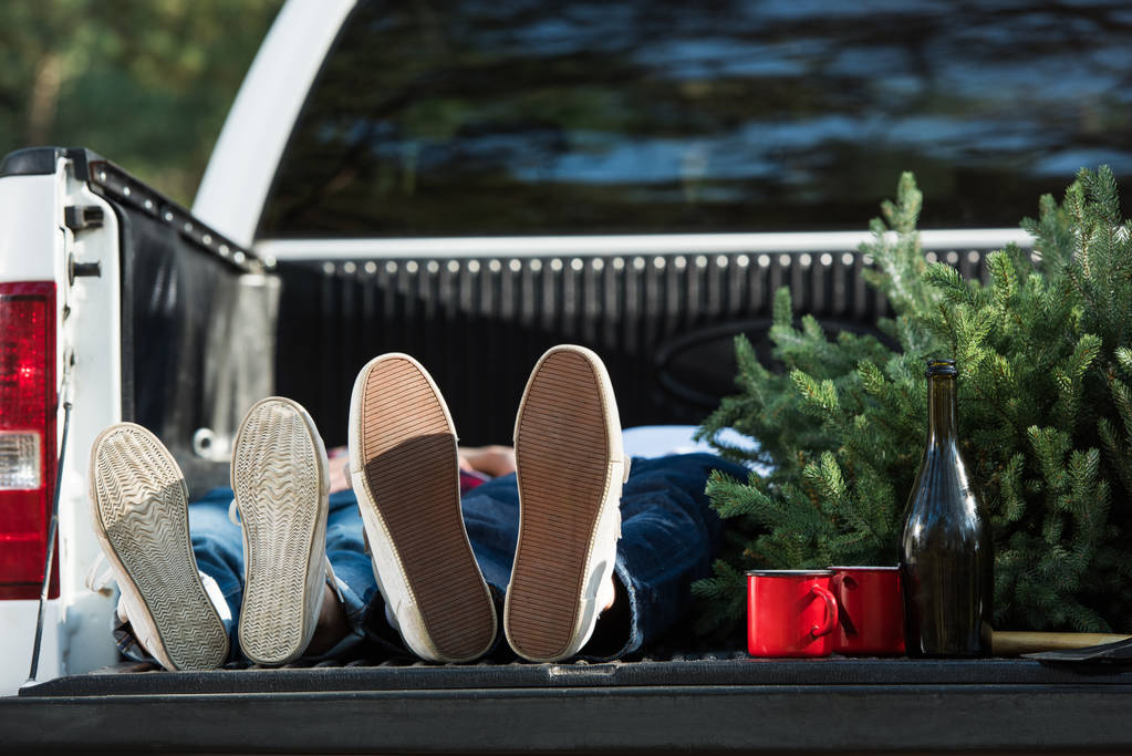 enfoque selectivo de pareja joven en el maletero del coche con árbol de Navidad y botella de champán al aire libre
  - Foto, Imagen