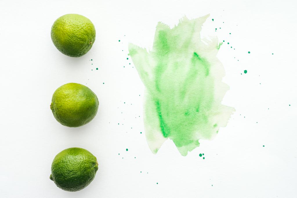 vista superior de limas maduras em linha na superfície branca com aquarela verde
 - Foto, Imagem