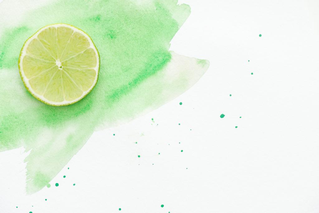 top view of piece of tasty lime on white surface with green watercolor - Photo, Image