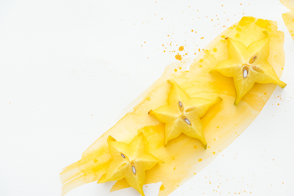 sarı suluboya ile beyaz yüzey üzerinde üç egzotik yıldız meyve üstten görünüm - Fotoğraf, Görsel