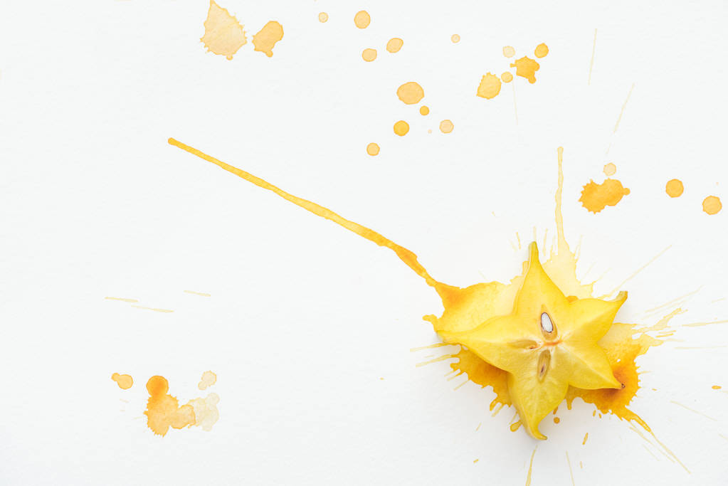 сверху вид экзотических звездных фруктов на белой поверхности с брызгами желтой краски
 - Фото, изображение