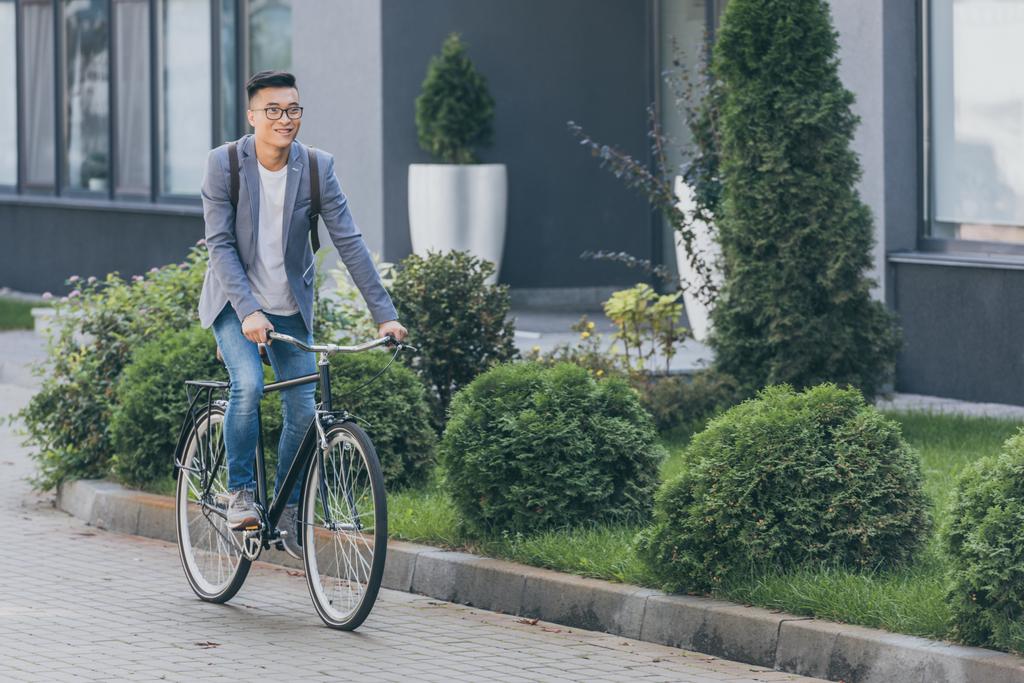 Stylový usměvavý Asiat na kole na kole ve městě - Fotografie, Obrázek