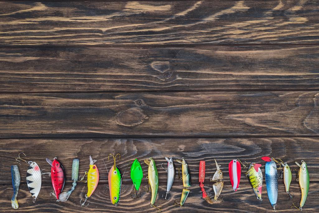 top view of various fishing bait placed in row on wooden background  - Photo, Image