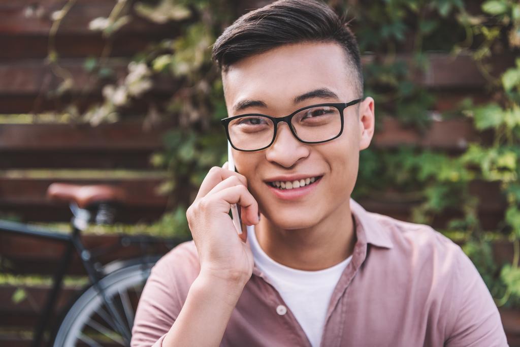 Portret van glimlachen Aziatische man in brillen praten op smartphone - Foto, afbeelding