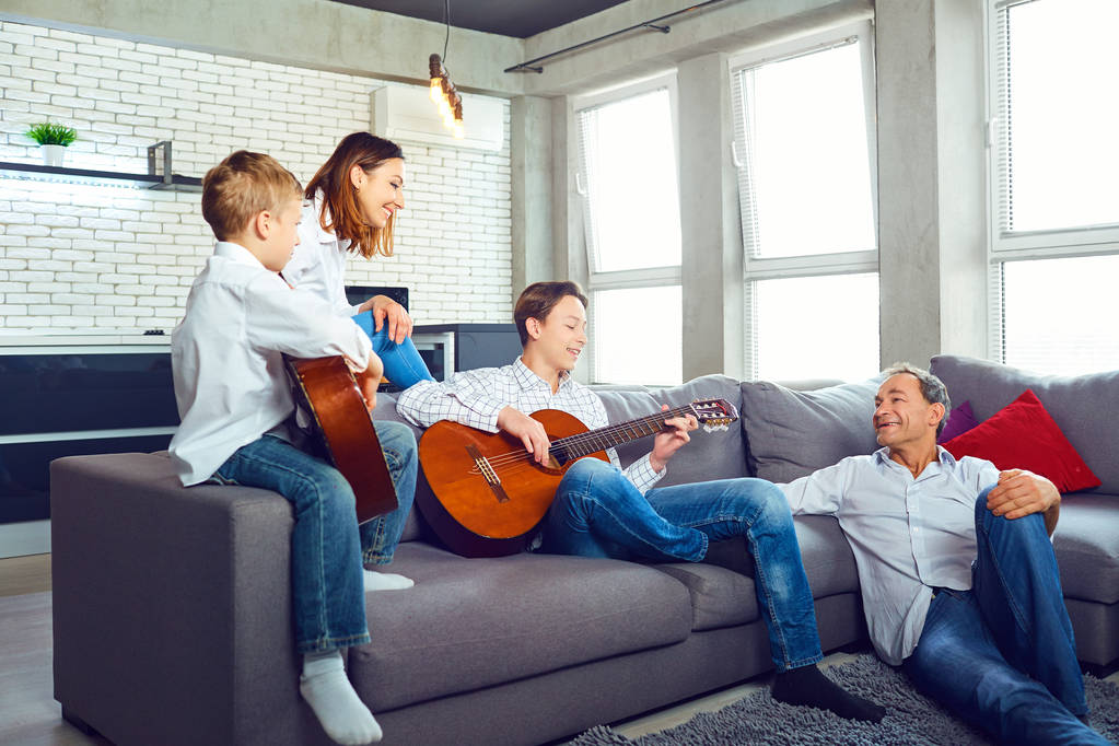 Joyeux famille avec des chansons de chant de guitare assis dans la chambre
 - Photo, image