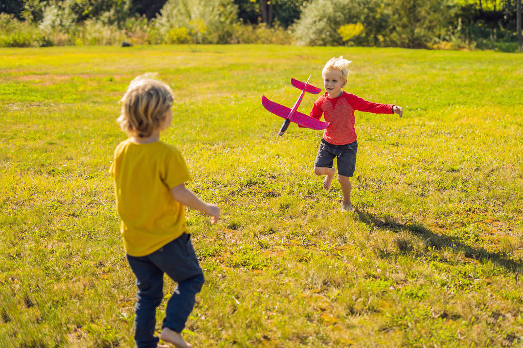 Dos chicos felices jugando con avión de juguete en el parque
 - Foto, Imagen