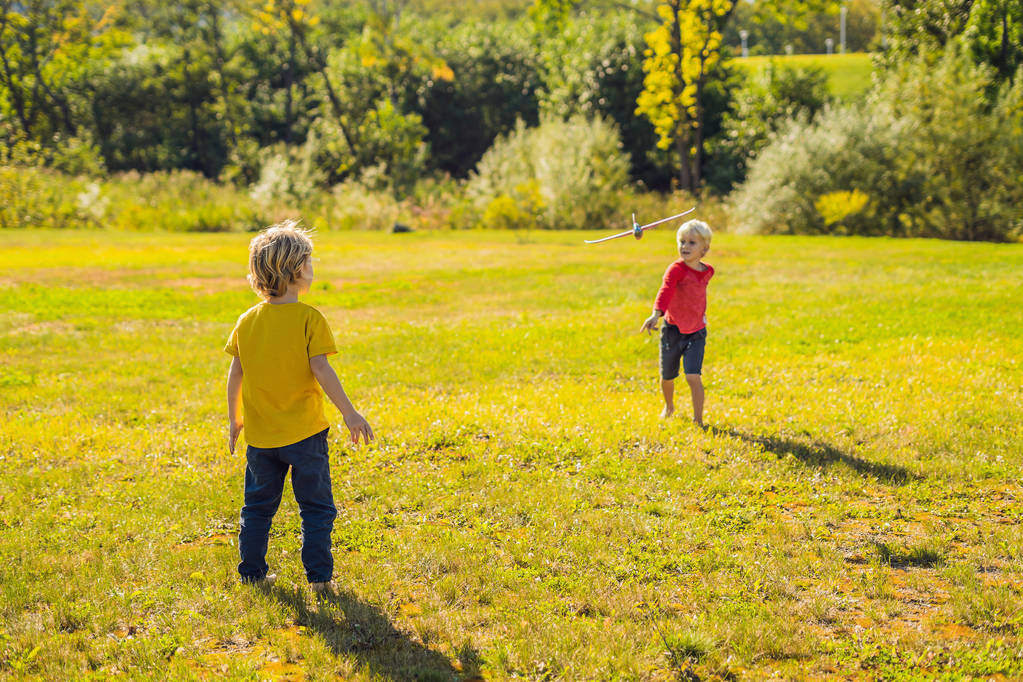 Dva šťastní kluci hrát s hračkou letadla v parku - Fotografie, Obrázek