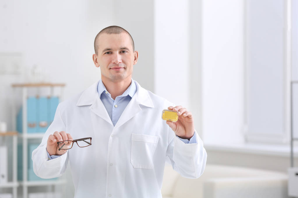 Αρσενικό ο γιατρός κρατάει θήκη φακών επαφής και γυαλιών σε εσωτερικούς χώρους - Φωτογραφία, εικόνα