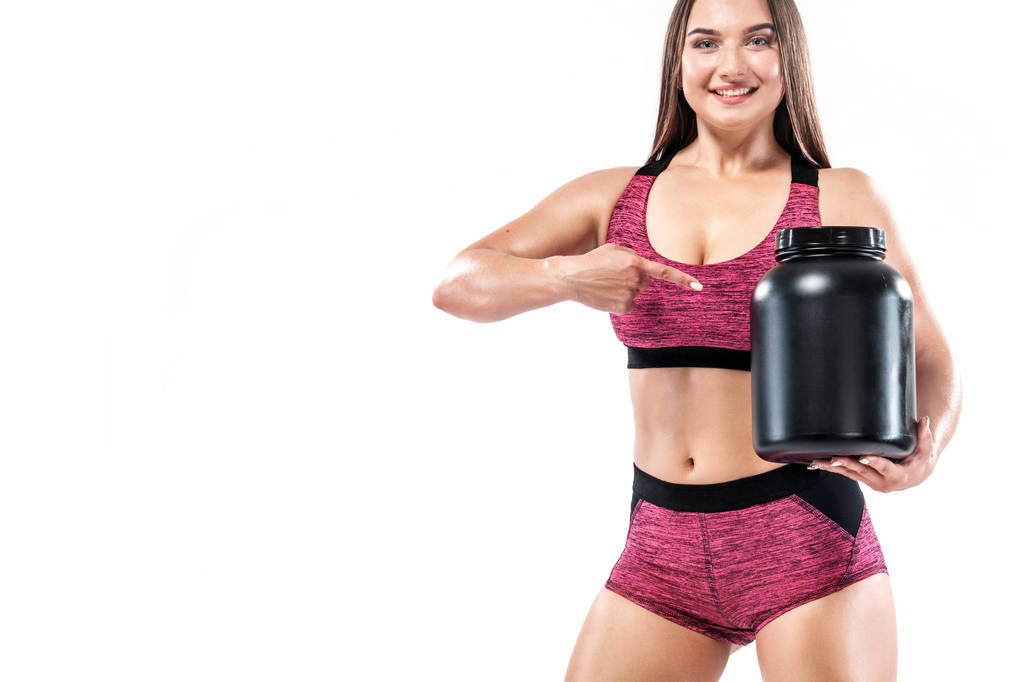 Ευτυχή και υγιή μυϊκή γυμναστήριο νεαρή γυναίκα αθλητής με ένα βάζο της αθλητικής διατροφής - πρωτεΐνη, κερδισμένος και καζεΐνη - Φωτογραφία, εικόνα