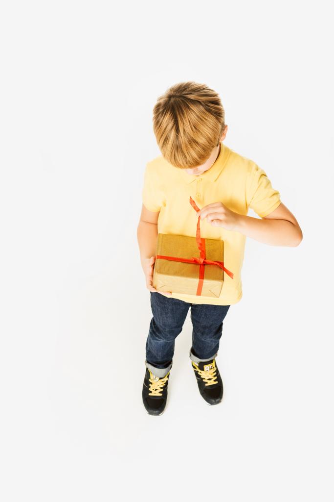 Hochwinkel-Ansicht von entzückenden kleinen Jungen öffnen Geschenkbox isoliert auf weiß - Foto, Bild