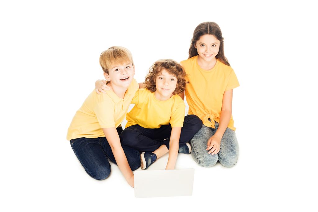 vista de ángulo alto de adorables niños felices utilizando el ordenador portátil y sonriendo a la cámara aislada en blanco
 - Foto, imagen