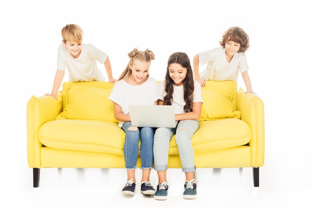 çocuk beyaz izole sarı kanepede dizüstü bilgisayar kullanarak - Fotoğraf, Görsel