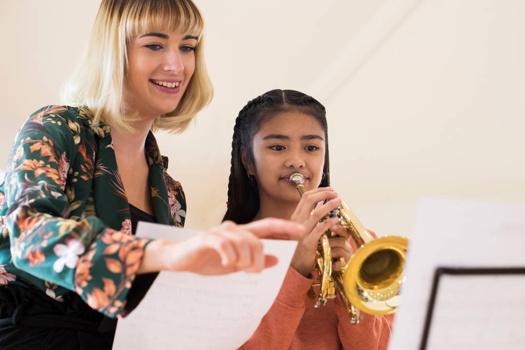Lehrerin hilft Schülerin beim Trompeten spielen im Musikunterricht - Foto, Bild