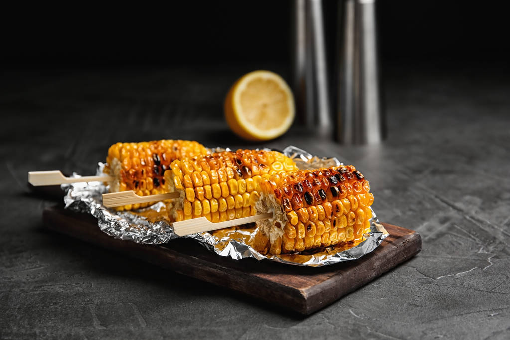 Deliciosas mazorcas de maíz a la parrilla en la mesa gris
 - Foto, imagen