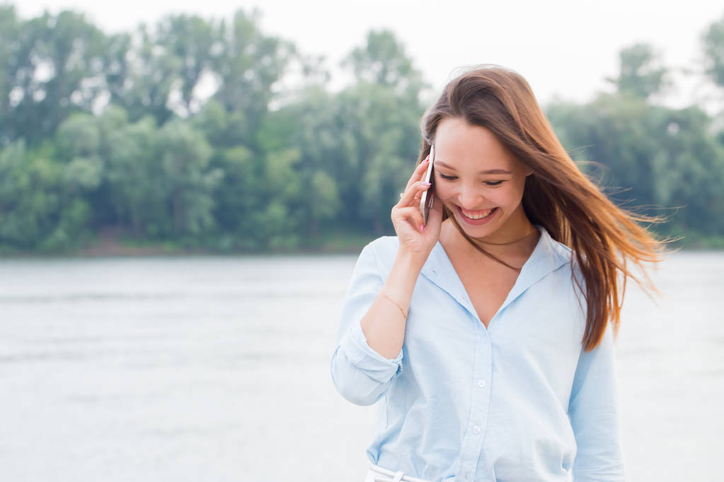 fröhliche junge Frau telefoniert und lacht laut am Ufer. moderne Technologie, Reisen, Lifestylekonzepte - Foto, Bild