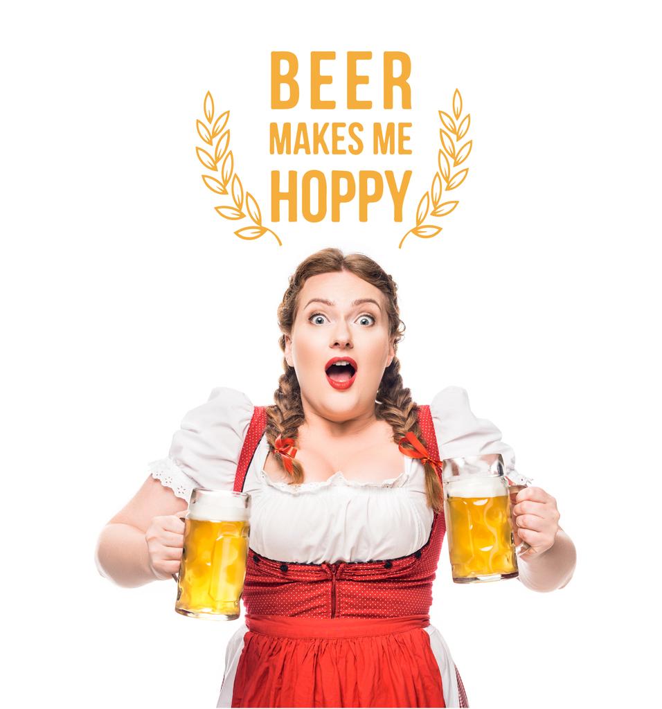 shocked oktoberfest waitress in traditional bavarian dress with mugs of light beer isolated on white background with "beer makes me hoppy" lettering - Photo, Image