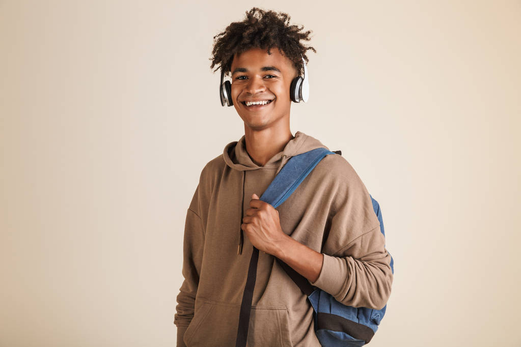Muotokuva iloinen nuori afro amerikkalainen mies pukeutunut huppari kuulokkeet kuljettavat reppu eristetty
 - Valokuva, kuva