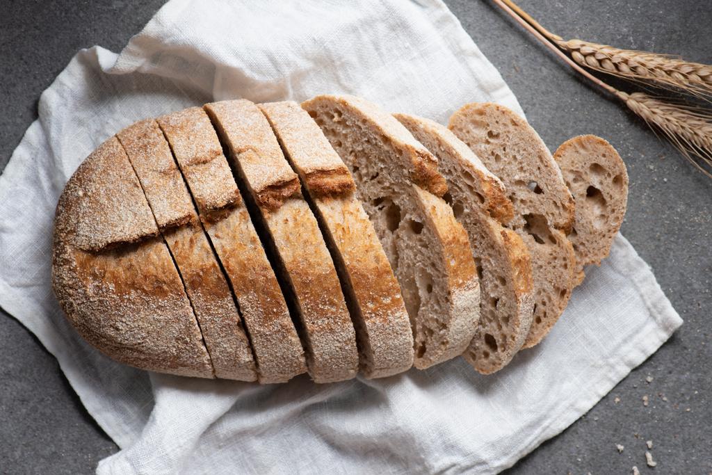 vlakke leggen met gesneden brood van brood op witte linnen op grijs tafelblad - Foto, afbeelding