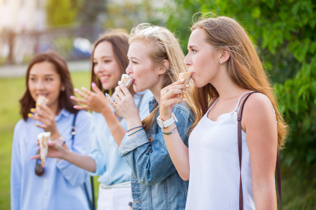 Čtyři radostné mladých přítelkyň stojící v řadě s úsměvem, spokojeně jíst zmrzlinu v parku. V létě, den volna - Fotografie, Obrázek