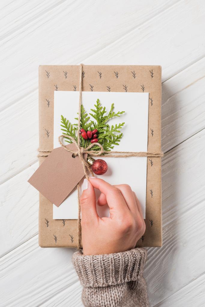 частковий вид жінки, що прикрашає різдвяну подарункову коробку за дерев'яним столом
  - Фото, зображення