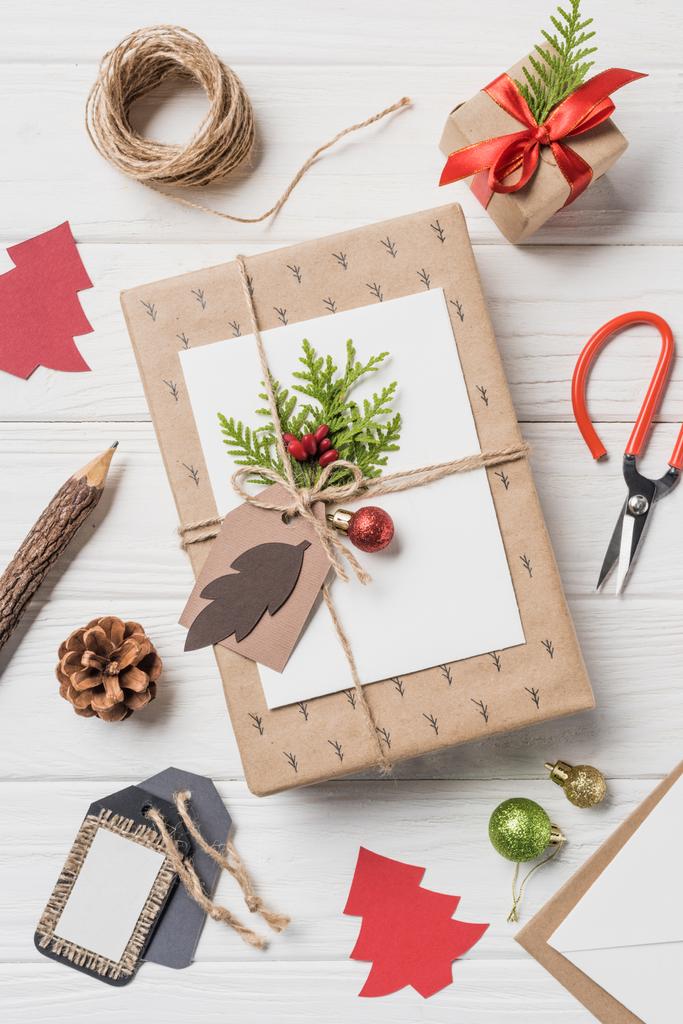 Draufsicht auf arrangierte Weihnachtsgeschenkboxen, Kugeln und immergrüne Kegel auf Holztisch - Foto, Bild