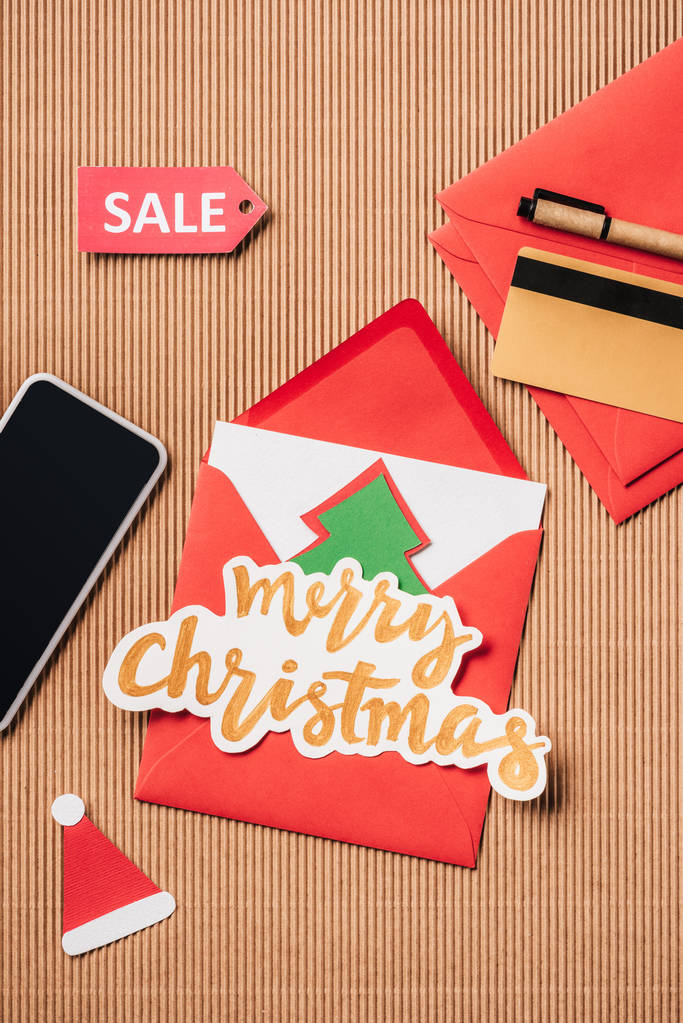 piatto laici con carta di credito, segno di vendita, busta Buon Natale e smartphone con schermo bianco sulla superficie
 - Foto, immagini