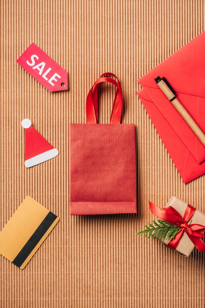 vista superior de la bolsa de compras roja, caja de regalo decorada, tarjeta de crédito y letrero de venta en la superficie
  - Foto, imagen