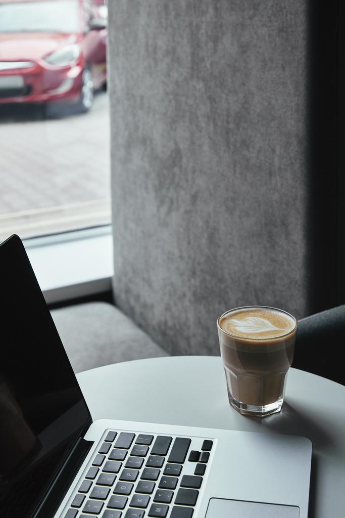 крупним планом вид на ноутбук з порожнім екраном і чашкою капучино на столі в кафе
  - Фото, зображення