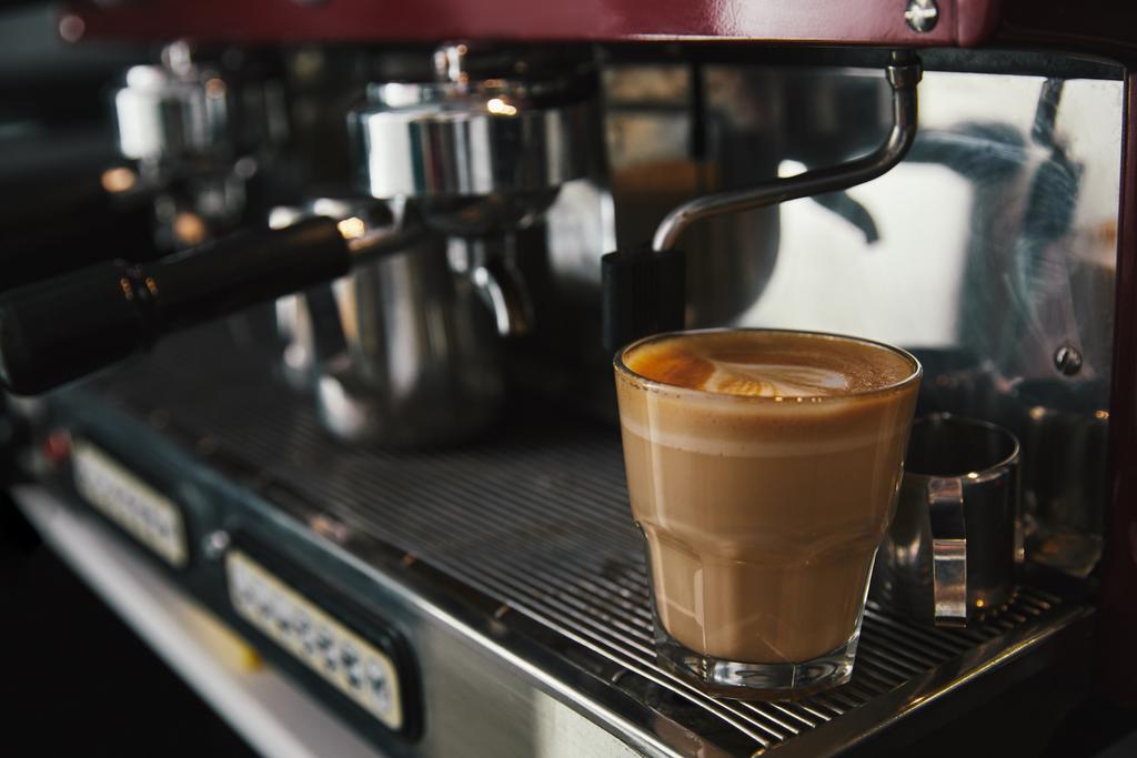 Крупный план стеклянной чашки с капучино и кофеваркой
 - Фото, изображение