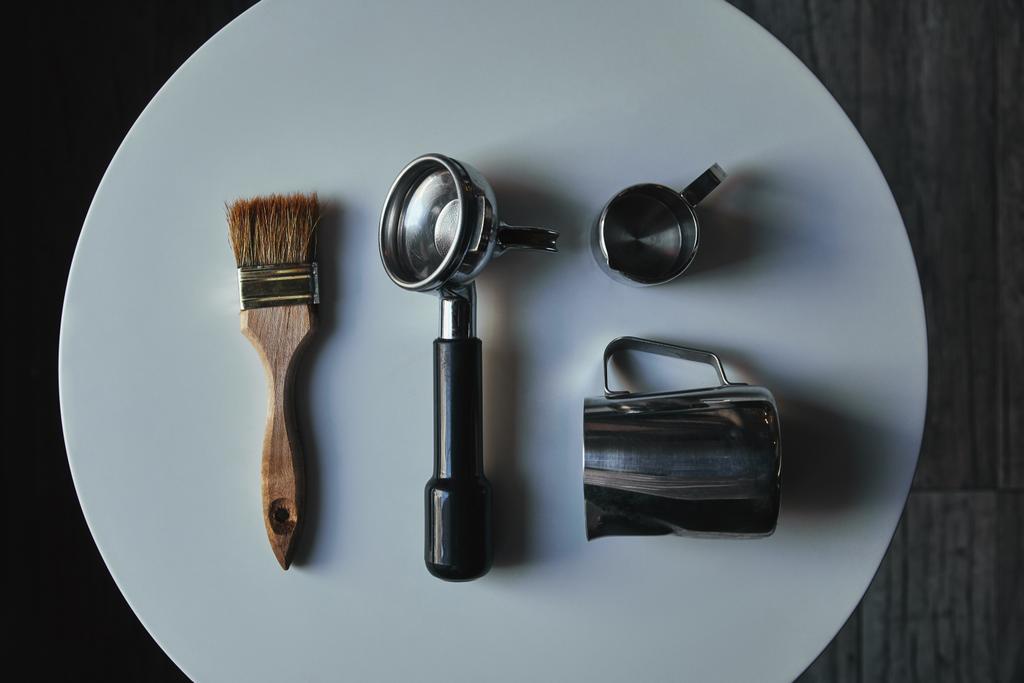 Ansicht von professionellen Werkzeugen zur Kaffeezubereitung auf rundem grauen Tisch - Foto, Bild
