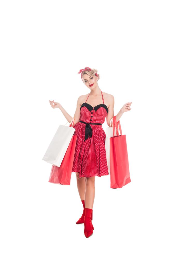 mujer joven en ropa retro pin up con bolsas de compras aisladas en blanco
 - Foto, Imagen
