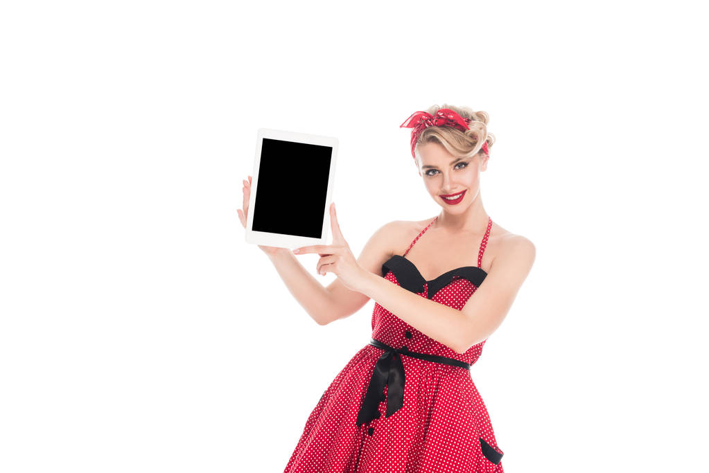 Porträt einer stilvollen Frau in Pin-up-Kleidung, die ein digitales Tablet mit leerem Bildschirm zeigt, isoliert auf weiß - Foto, Bild