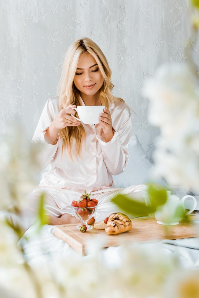 schöne Frau im Pyjama trinkt morgens Tee im Bett - Foto, Bild