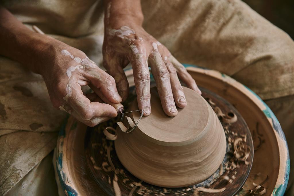 close up view of professional potter decorating clay pot at workshop - Photo, Image