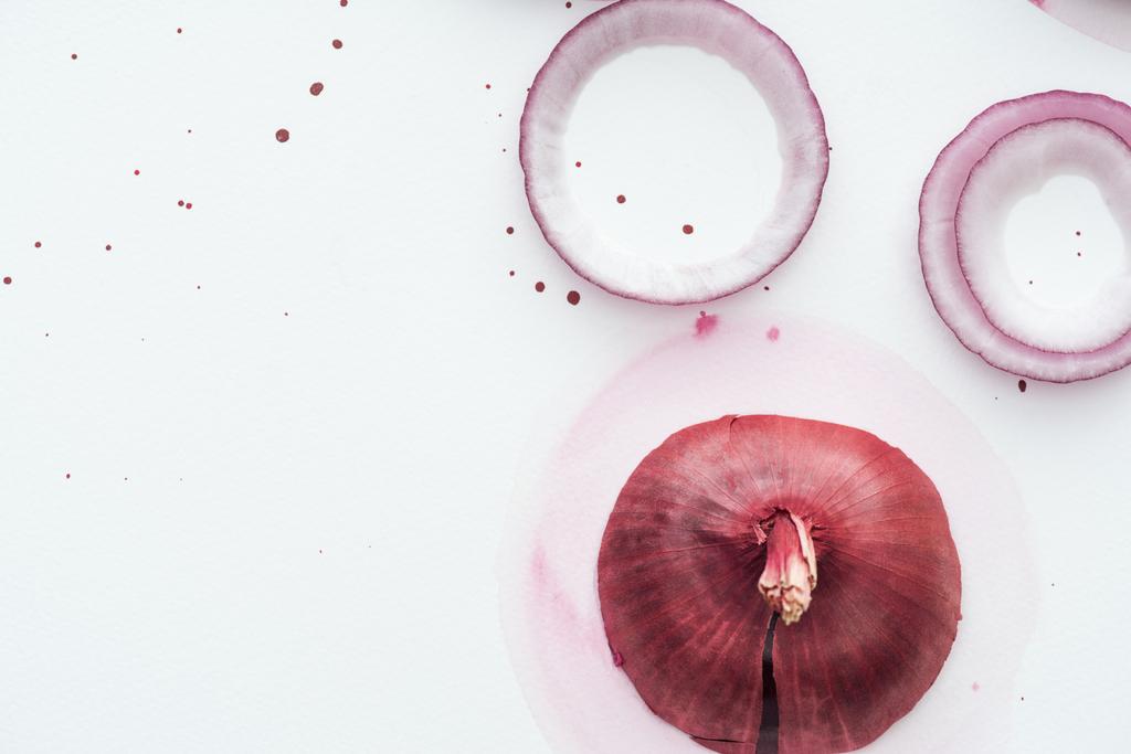 vista superior de cebolla roja entera con anillos en la superficie blanca con manchas de acuarela rosa
 - Foto, Imagen