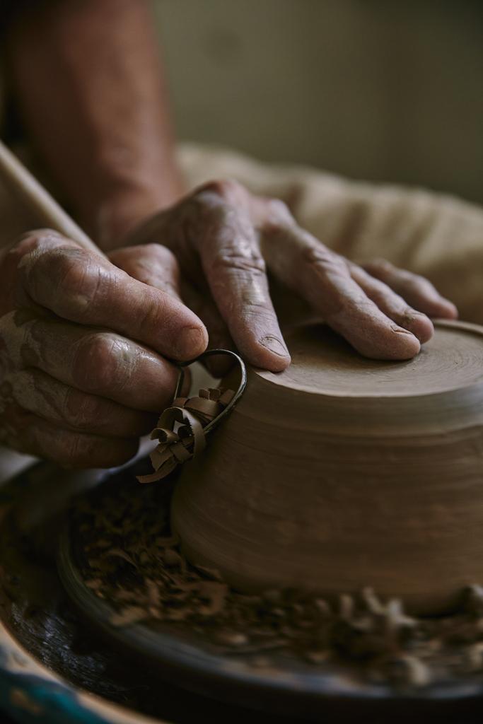 Крупный план профессионального гончара, украшающего глиняный горшок в мастерской
 - Фото, изображение