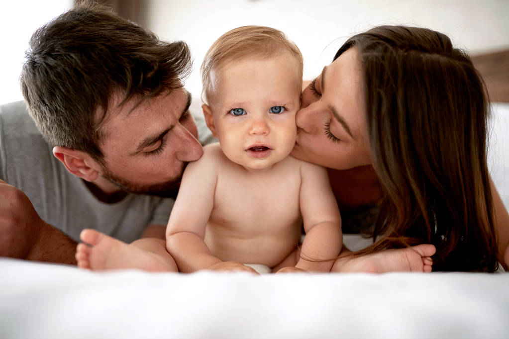 Family with kid in the morning. Young mother, father kissing beautiful baby child - Photo, Image