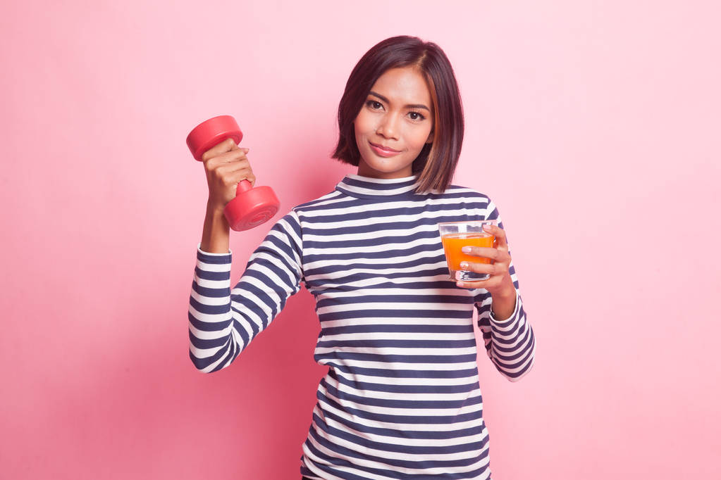 Mladá asijská žena s činka pít pomerančovou šťávu na růžovém pozadí - Fotografie, Obrázek