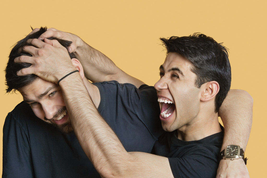 Young male friends playfighting over colored background - Photo, Image