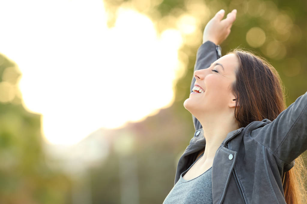 Porträt einer glücklichen Dame, die frische Luft atmet und die Arme in einem Park hebt - Foto, Bild